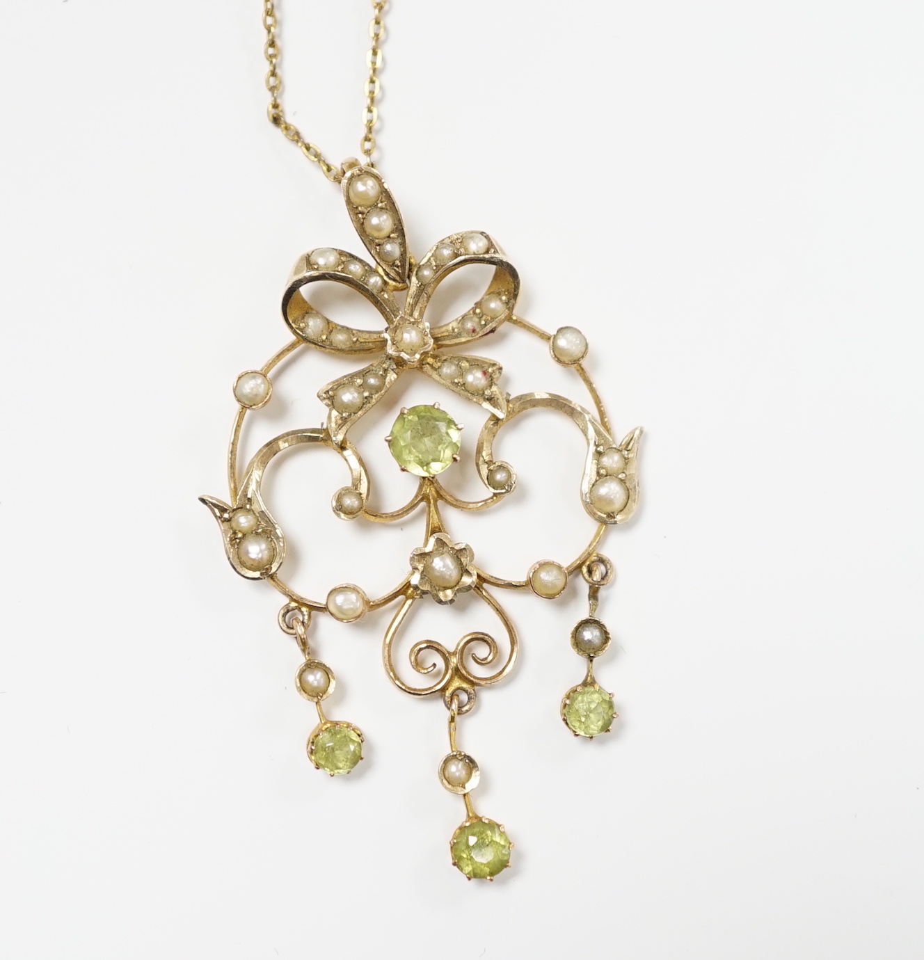 An Edwardian 9ct, peridot and seed pearl cluster set drop pendant, 47mm, on a gilt metal chan.